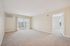 Bright and inviting living room with plush carpet, large sliding glass doors, and access to a spacious bedroom.| Village Green | Apartment in Tewksbury, MA