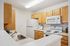 Modern kitchen with elegant wooden cabinets, sleek countertop, and essential appliances including a stovetop, microwave, and refrigerator.| Village Green | Apartment in Tewksbury, MA