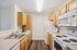 Modern kitchen with sleek countertops, light wood cabinetry, and high-end appliances for a contemporary living experience.| Village Green | Apartment in Tewksbury, MA