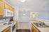 Inviting kitchen with warm wooden cabinets, sleek countertops, and modern appliances, leading into an open, well-lit living space perfect for entertaining.| Village Green | Apartment in Tewksbury, MA