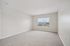 Bright and airy bedroom with soft carpeting, large window offering natural light, and neutral wall tones.| Village Green | Apartment in Tewksbury, MA
