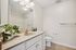 Elegant bathroom with a sleek countertop, large mirror, and vibrant floral decor, offering a refined and modern aesthetic.| Village Green | Apartment in Tewksbury, MA