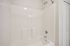 Elegant bathroom with a pristine white bathtub featuring modern fixtures, offering a clean and inviting space.| Village Green | Apartment in Tewksbury, MA