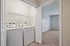 Modern apartment featuring an in-unit laundry area with a washer and dryer, complemented by a spacious carpeted room.| Village Green | Apartment in Tewksbury, MA