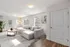 Bright and inviting living room featuring a plush gray sectional sofa, elegant coffee table, and natural light streaming through large windows.