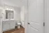 Elegant modern bathroom with sleek white vanity, polished fixtures, and hardwood flooring, perfect for a stylish home.