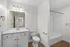 Elegant bathroom with modern fixtures, featuring a pristine white vanity, stylish mirror, and a spacious bathtub with sleek white interiors.