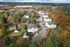 Aerial view of elegant apartment complex nestled among vibrant autumn trees and extensive greenery, offering a serene and picturesque living environment.