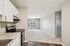 Chic apartment with sleek kitchen, modern appliances, and sunlit living area boasting floor-to-ceiling windows.