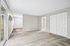 Bright and spacious living area with a large window, plush carpet, and sleek closet doors, offering a comfortable and stylish atmosphere.
