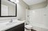 Modern bathroom featuring a sleek vanity with a large mirror and a pristine white bathtub, offering both style and comfort.