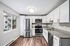 Modern kitchen with stainless steel appliances, granite countertops, and sleek white cabinetry, featuring a bright window view.