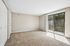 Bright and airy living room with plush carpet, large sliding glass doors opening to a serene view of nature.
