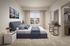 Elegant bedroom with plush carpet, stylish bedding, and a modern side table, featuring natural light through a large window and a spacious walk-in closet.