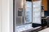 Modern stainless steel refrigerator with French doors open, showcasing spacious and well-lit interior, perfect for a contemporary kitchen.