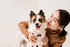 Heartwarming moment of a smiling woman hugging her adorable dog in a cozy setting.