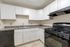 Modern kitchen with sleek black appliances, abundant white cabinetry, and elegant stone countertops.