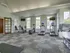 Fitness center with treadmills, stationary bikes, elliptical machine, and leg press, featuring large windows and modern decor.