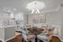 Elegant dining area with cozy round table set and modern kitchen, featuring sleek white cabinetry and stainless steel appliances.