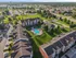 Stunning aerial view of a modern apartment complex with lush green landscaping and inviting circular pool, nestled in a vibrant suburban neighborhood.