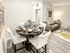Elegant open-concept apartment featuring a stylish dining area with a modern table set, cozy living space with a sleek sofa, and contemporary decor.
