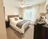 Bright and inviting bedroom featuring a cozy bed with elegant decor, large window with serene outdoor view, and stylish furnishings.