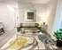 Modern apartment living room with sleek decor, featuring a comfortable taupe sofa, stylish glass coffee table, and contemporary artwork, illuminated by soft lighting and accessorized with a vibrant area rug and lush green plant.