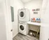 Modern laundry room with elegant stacked washer and dryer, stylish shelving for organized storage, and chic decor accents.