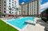 Luxurious apartment building with a stunning outdoor pool surrounded by palm trees and modern amenities, perfect for relaxation and leisure.