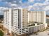 Modern high-rise apartment building with a rooftop garden and panoramic city views under a vibrant sky.