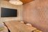 Chic meeting room with elegant wood table, cozy leather chairs, modern flat-screen TV, and stylish geometric wallpaper.