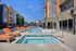 Contemporary apartment complex with a luxurious outdoor pool and vibrant orange lounge chairs under a clear blue sky.