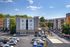 Chic apartment complex featuring modern architecture, lush greenery, ample parking, and inviting pool area under a vibrant blue sky.