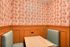 Charming dining nook with vintage-inspired orange and white forest wallpaper, cozy booth seating, and elegant wainscoting, perfect for intimate meals.