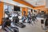 Modern fitness center with state-of-the-art cardio equipment and vibrant orange accents, offering a refreshing workout environment.
