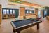 Modern recreational room with a sleek pool table, stylish seating area, and vibrant ceiling artwork, perfect for entertainment and relaxation.
