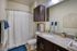 Elegant bathroom featuring a stylish granite countertop, modern dark wood cabinetry, and a soft white shower curtain accented with luxurious blue towels for a tranquil feel.