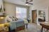 Inviting bedroom with elegant decor, cozy bedding, large window with natural light, stylish ceiling fan and a mirrored closet.