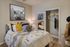 Cozy bedroom with stylish bedding, modern decor, and a built-in closet, illuminated by a warm lamp.