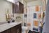 Modern bathroom with elegant dark wood cabinets, granite countertop, and vibrant geometric shower curtain. Stylish touches include framed art and decorative succulents, creating a welcoming and serene atmosphere.