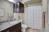 Elegant bathroom with granite countertop, sleek dark wood cabinets, and a neatly hung shower curtain, exuding warmth and style.