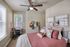 Charming bedroom with plush pillows, stylish decor, and natural light pouring through large windows.