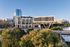Modern luxury building 'One Rangers Way' with sleek architecture set against a scenic backdrop of lush greenery and adjacent to a shimmering waterfront.