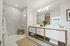 Luxurious bathroom featuring a modern glass-enclosed shower, sleek double vanity, and elegant lighting with a view to tranquil surroundings.