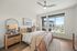 Elegant bedroom with large windows, modern decor, and a cozy ambiance in a bright and airy space.