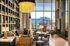 Luxurious club lounge featuring a cozy seating area with plush sofas, elegant leather chairs, and a dazzling chandelier against a backdrop of floor-to-ceiling windows with a stadium view.