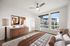 Bright and modern bedroom with large windows offering a view of contemporary architecture, featuring stylish decor and elegant furniture.