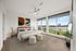 Modern bedroom with large windows offering scenic views, stylish decor, and cozy furnishings.
