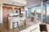 Modern open-concept kitchen with sleek wooden cabinetry, stylish island with seating, and dining area with panoramic city views through expansive windows.