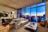 Modern living room with floor-to-ceiling windows offering a stunning cityscape view at sunset, featuring elegant furniture and stylish decor.